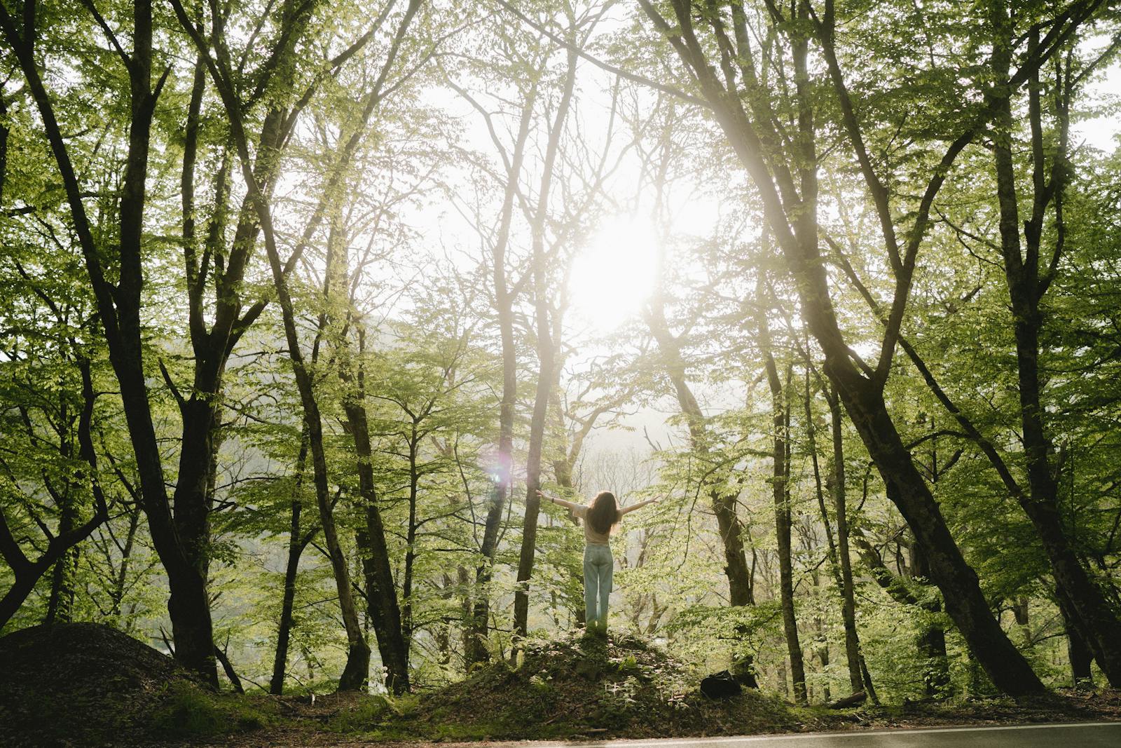 Femme souriante bras ouverts en forêt, sentiment de libération après une séance de sophrologie